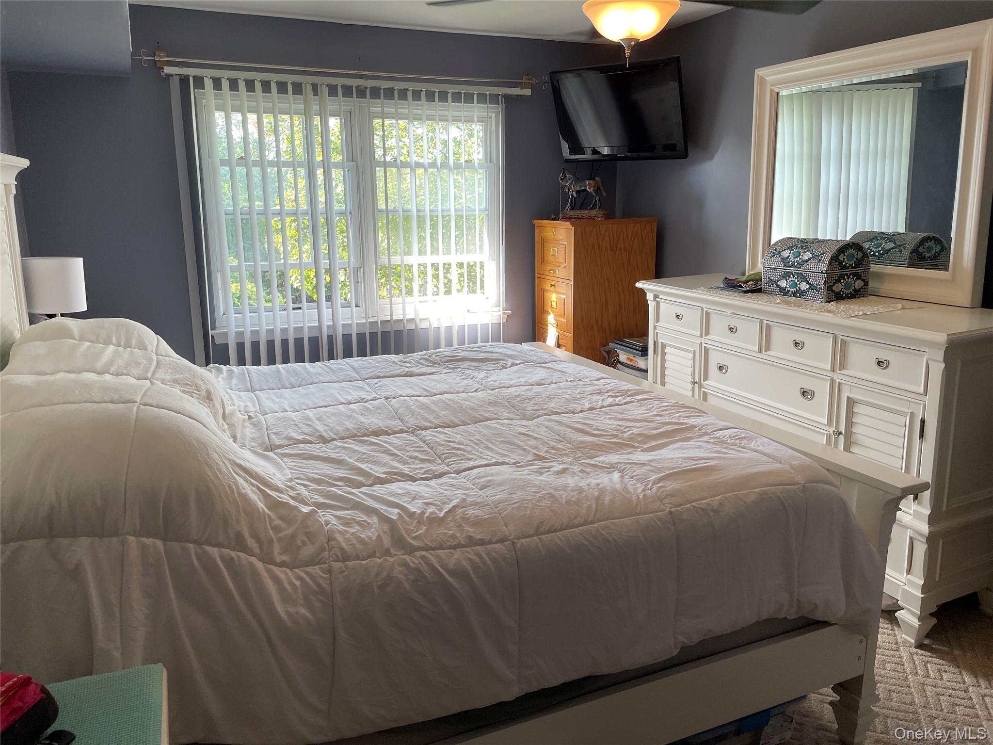 107 Mariners Way Copiague, NY 11726 - Photo 18 of 27 a bedroom with a bed and a lamp with window