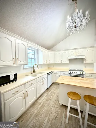 a large white kitchen with wooden floor and stainless steel appliances