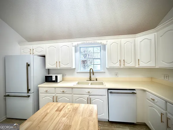 a kitchen with a sink a refrigerator and cabinets