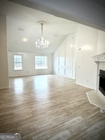 a view of an empty room with window and wooden floor