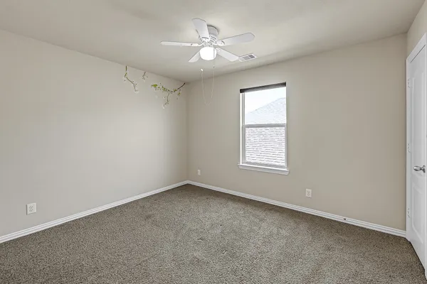 an empty room with a window and a ceiling fan