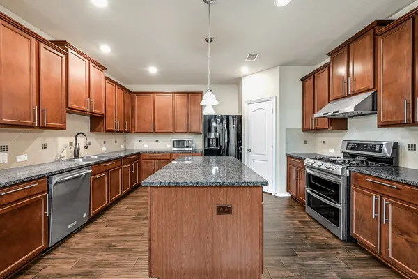 a large kitchen with stainless steel appliances granite countertop a stove sink refrigerator and cabinets