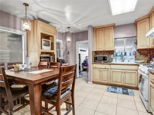 a kitchen with stainless steel appliances granite countertop a stove a sink dishwasher a dining table and chairs with wooden floor