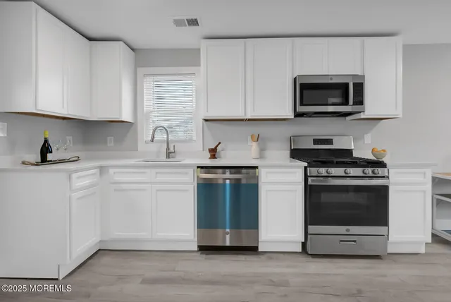 a kitchen with stainless steel appliances granite countertop a stove a sink and a microwave