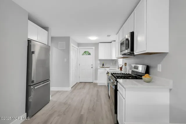 a kitchen with stainless steel appliances a refrigerator a sink a stove a microwave and wooden floor