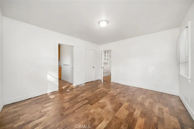 an empty room with windows and view of kitchen