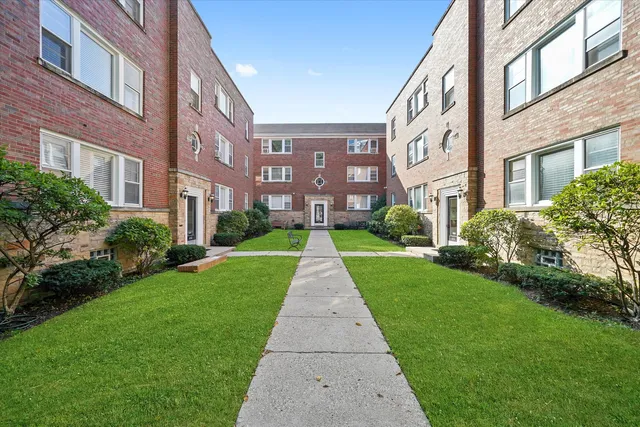 a view of a brick house next to a yard with big trees
