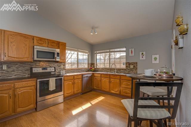 6150 Rabbit Ears Court Colorado Springs, CO 80919 - Photo 8 of 31 a kitchen with stainless steel appliances granite countertop a stove top oven a sink dishwasher a dining table and chairs with wooden floor