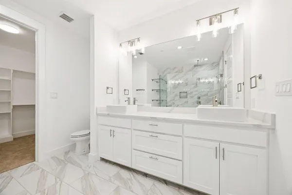 a bathroom with a double vanity sink mirror and toilet
