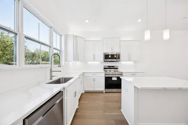 a kitchen with stainless steel appliances granite countertop a sink a stove and a refrigerator