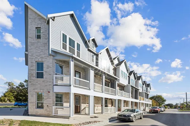 a front view of a building with lot of cars and trees