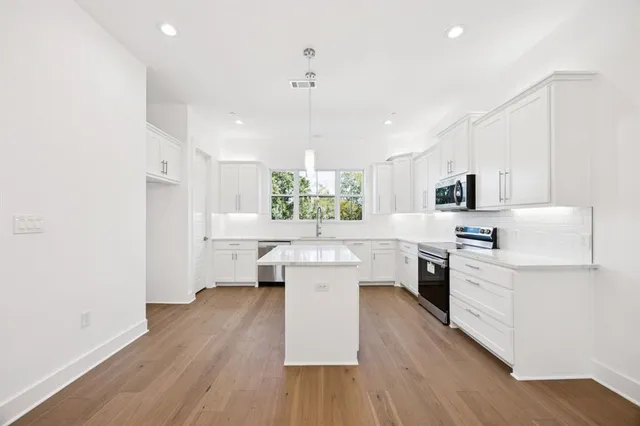 a large kitchen with a lot of counter space and wooden floor