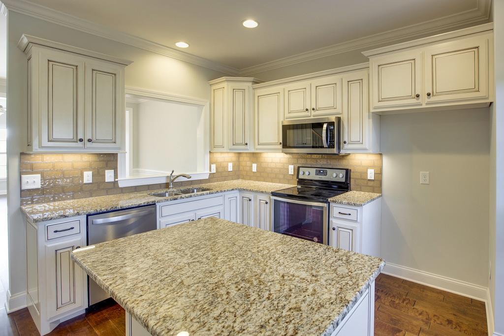 4325 Glassgow Road Spring Hill, TN 37174 - Photo 9 of 28 a kitchen with granite countertop wooden cabinets and a stove top oven