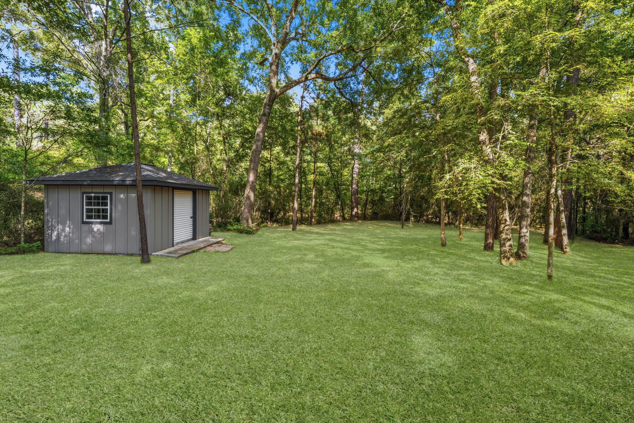 248 Fire Sky Road Huntsville, TX 77340 - Photo 34 of 36 Expansive backyard view highlights the open lawn, mature trees and additional outbuildings, with plenty of room to enjoy the acreage.