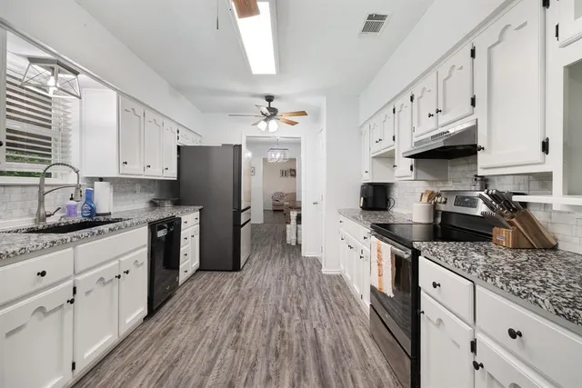 a kitchen with granite countertop a sink cabinets stainless steel appliances and a window