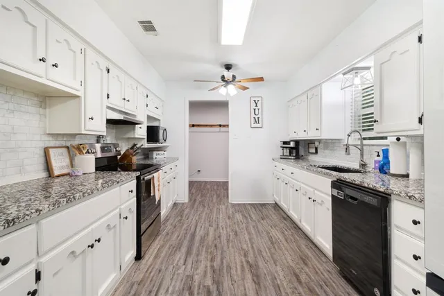 a kitchen with granite countertop a sink cabinets stainless steel appliances and a window