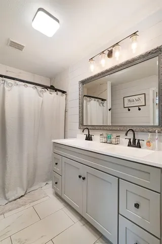 a spacious bathroom with a double vanity sink a mirror and shower