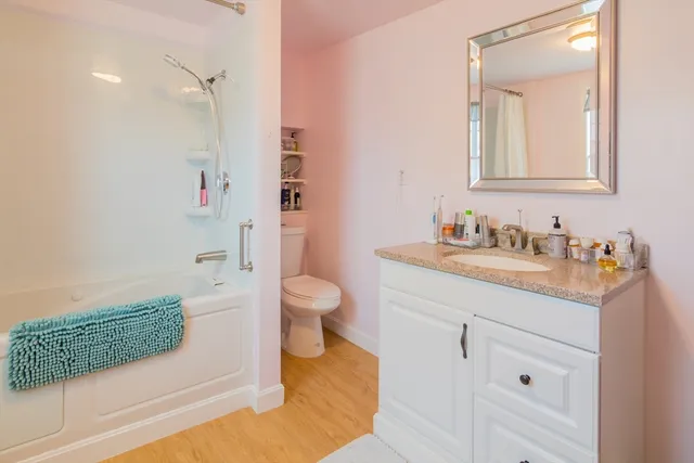 a spacious bathroom with a granite countertop sink a toilet and a mirror