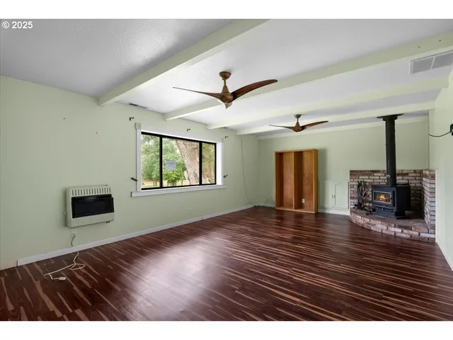 a view of an empty room with window and wooden floor