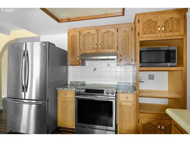 a kitchen with stainless steel appliances granite countertop a refrigerator a stove and a sink with wooden floor