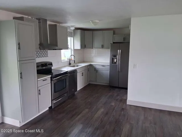 a kitchen with a sink a refrigerator a microwave and cabinets