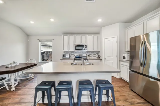 a kitchen with granite countertop a refrigerator and a stove top oven