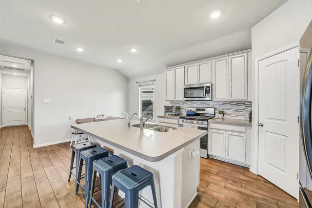 a kitchen with a sink stainless steel appliances and white cabinets