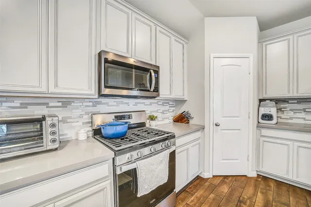 a kitchen with granite countertop cabinets stainless steel appliances and wooden floor