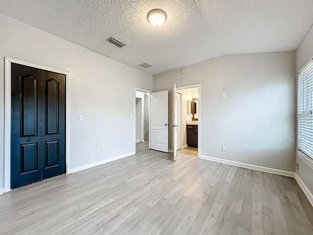 a view of an empty room with wooden floor and closet