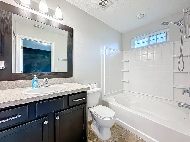 a bathroom with a granite countertop sink toilet mirror and bathtub