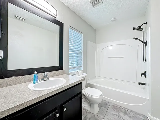 a bathroom with a granite countertop sink toilet a mirror and bathtub