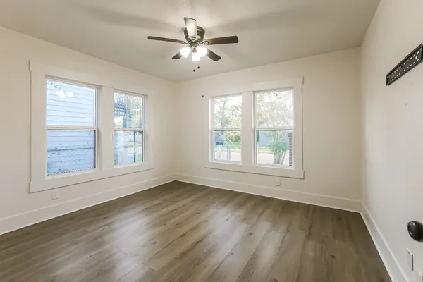 a view of an empty room with wooden floor and a window