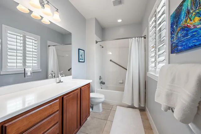 a spacious bathroom with a sink a toilet a mirror a vanity and a shower