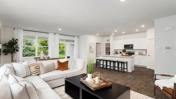 a living room with furniture kitchen view and a large window