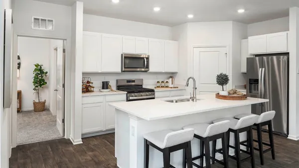 a kitchen with stainless steel appliances a table chairs refrigerator and microwave