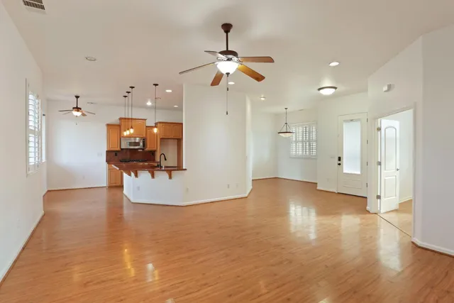 a kitchen with stainless steel appliances granite countertop a stove top oven a sink a dining table and chairs with wooden floor