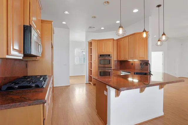 a kitchen with stainless steel appliances granite countertop a sink a stove and a microwave