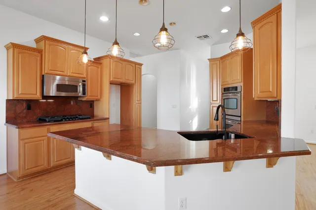 a view of a kitchen with stainless steel appliances wooden cabinets and a counter top space