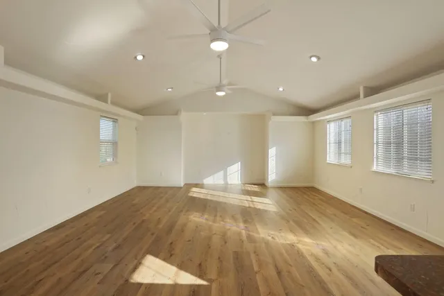 a view of an empty room with window and wooden floor