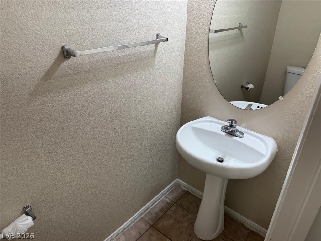 3962 Coyote Ridge Court Las Vegas, NV 89129 - Photo 16 of 35 A compact and functional powder room with a pedestal sink and tile flooring.
