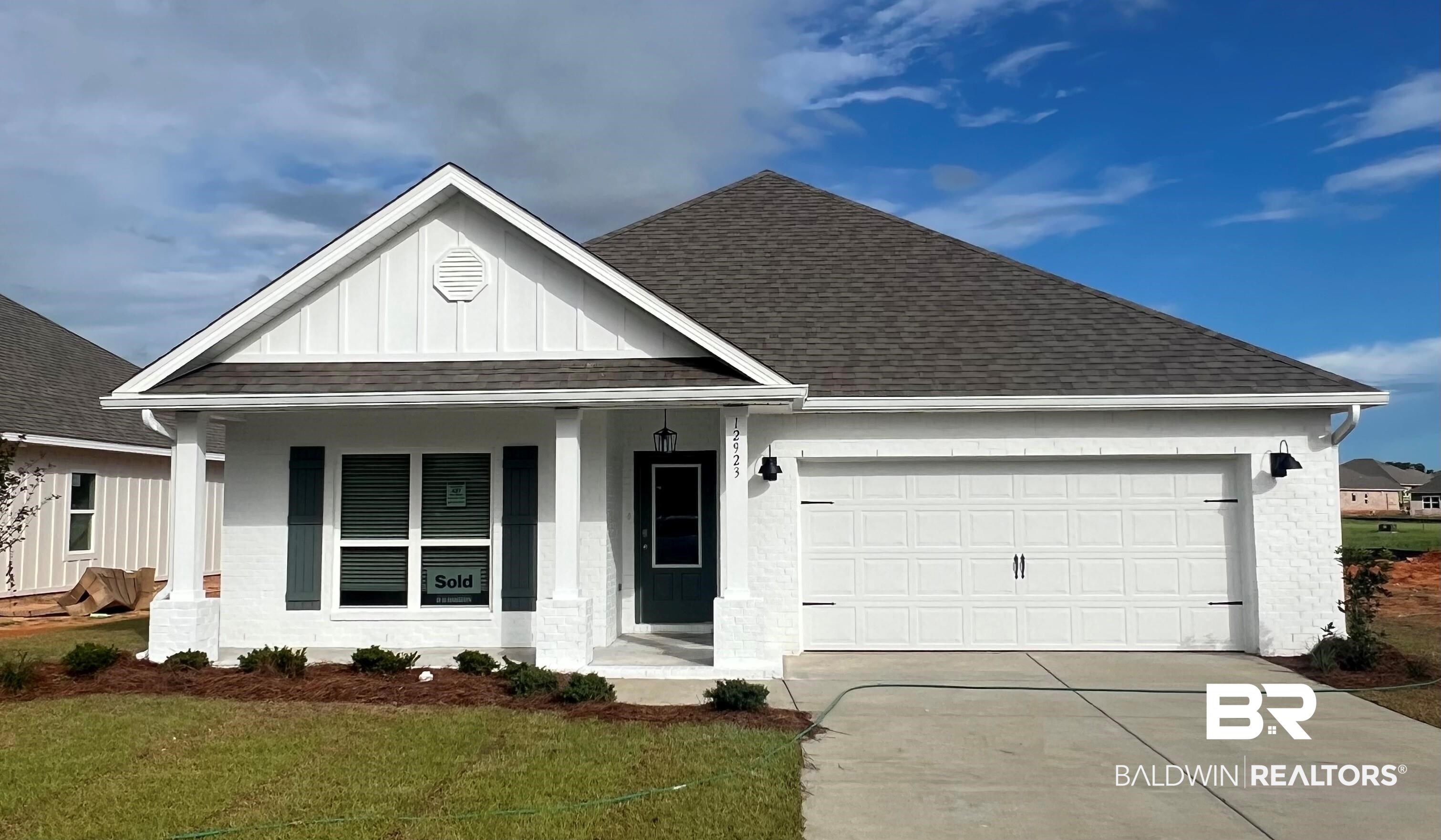 View of front of house with a garage, a porch, and a front lawn