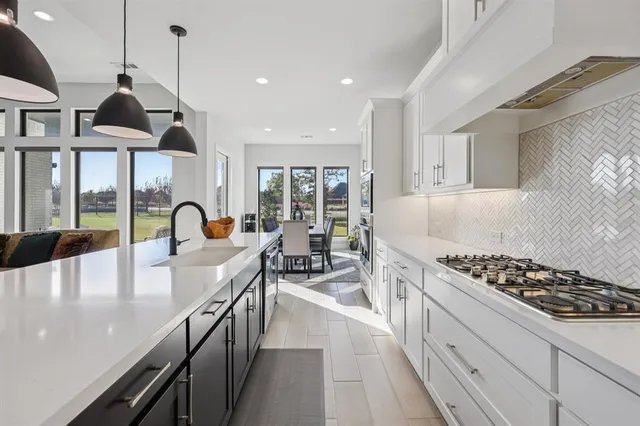 a kitchen with stainless steel appliances a stove a sink a counter space and living room view