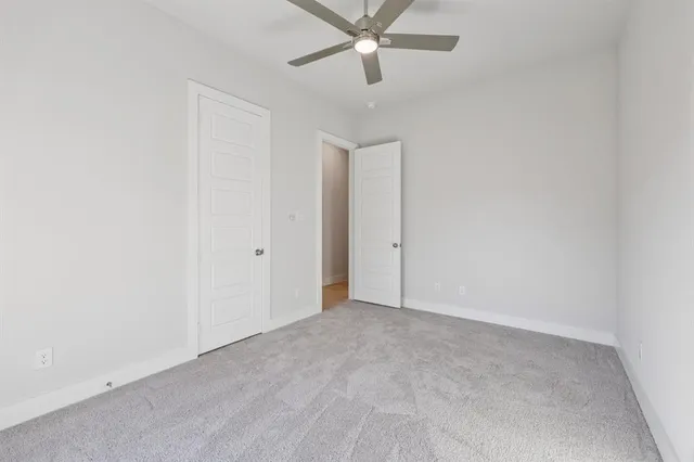an empty room with a ceiling fan and carpet