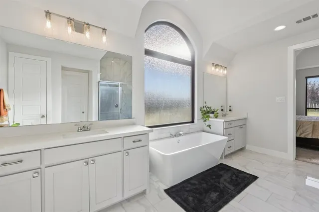 a spacious bathroom with a double vanity sink a mirror and a bathtub