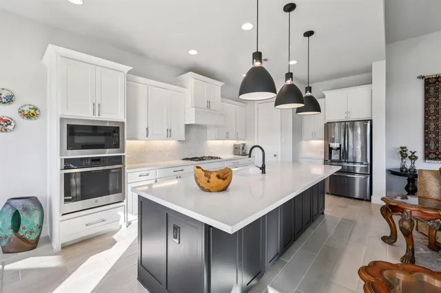 a kitchen with stainless steel appliances kitchen island a stove a sink a refrigerator and chairs