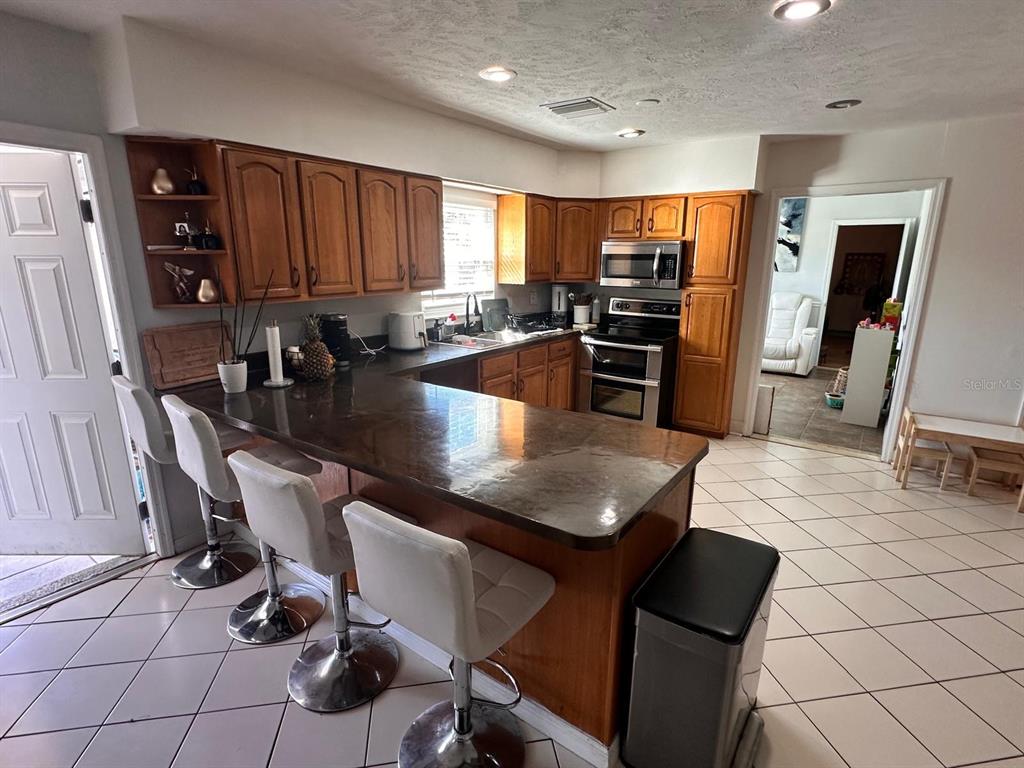 613 Royal Crest Way Brandon, FL 33511 - Photo 15 of 50 a kitchen with granite countertop a refrigerator a stove a sink a dining table and chairs with wooden floor