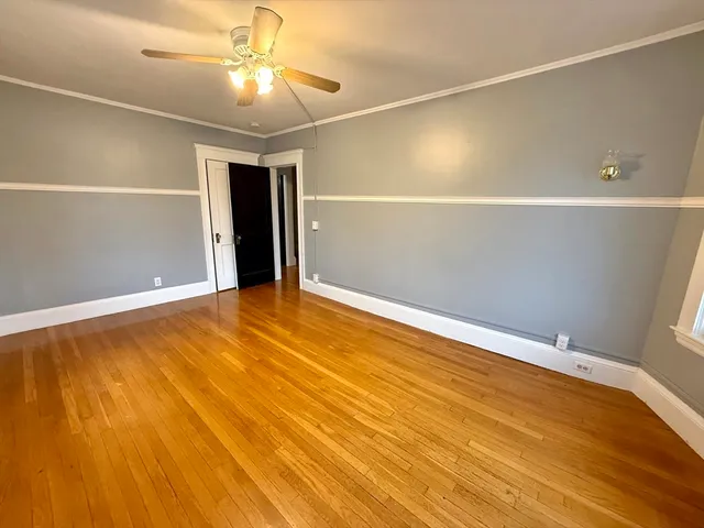 an empty room with wooden floor and windows with curtains