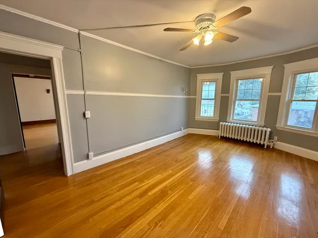 a view of empty room with wooden floor and fan