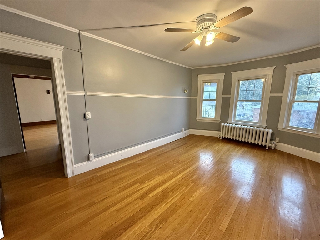 4 Adams Avenue, Unit 2 Watertown, MA 02472 - Photo 12 of 32 an empty room with wooden floor and windows with curtains