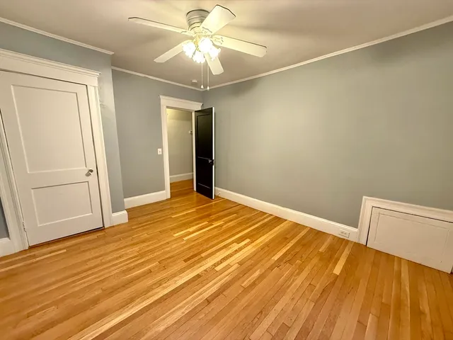 an empty room with wooden floor and fan
